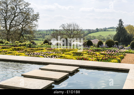 Zierteich im Garten von Broughton Grange, Oxfordshire mit Knoten Garten im Bereich Walled Garden. Stockfoto