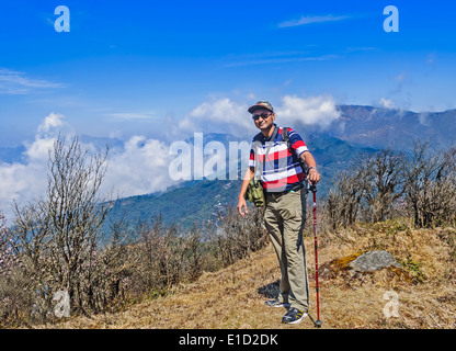 Ein Trekker Reisender auf einem Hügel beim trekking durch die Berge des Himalaya mit Gehstock, Wolke, Himmel, Büsche mit Textfreiraum Stockfoto