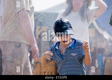 Tewkesbury Mittelalterfest, Gloucester UK Juli 2013: kleiner Junge spielt in Spritzwasser an einem sehr warmen sonnigen Tag Abkühlung Stockfoto