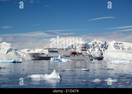 Eine Antarktis Kreuzfahrt Schiff mit aufblasbaren Schlauchboote auf dem ruhigen Wasser unter den Eisschollen und bergige Landschaft. Stockfoto