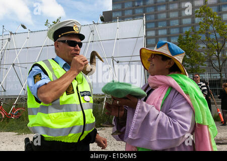 Kopenhagen, Dänemark. 31. Mai 2014. Kopenhagen, Dänemark - 31. Mai 2014: Polizist an der Bilderberg-treffen"Demonstranten" vor dem Marriott Hotel (links, hinten) nimmt "Dialog" zu neuen Höhen. Dänische Polizei in Kopenhagen haben für das letzte Jahr an ein neues Konzept, wo sie während der Demonstrationen fügt ein "Dialog-Unit" gearbeitet, in der Demonstration um bauen Beziehungen auf die Demonstranten und Konflikte sprechen. Auf dem Foto eine kreative Demonstrator (rechts) behauptet, dass ihr Ram Horn magische Kommunikationsfähigkeiten hat, der Polizist ausprobieren. © OJPHOTOS/Alamy L Stockfoto