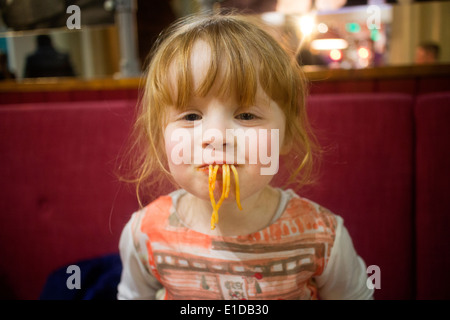 Vier 4 Jahre altes Mädchen im Restaurant Essen Spaghetti mit Nudeln aus dem Mund hängen Stockfoto