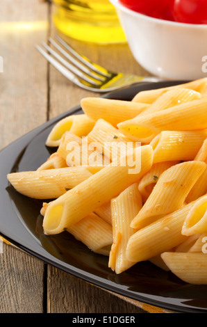 Pasta Penne in Platte auf hölzernen Hintergrund Stockfoto