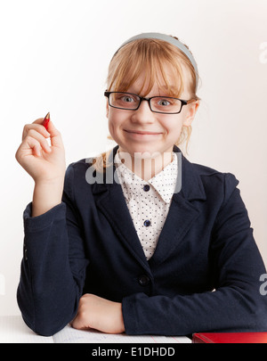 Kleines blondes Schulmädchen mit Brille hält den Stift Stockfoto