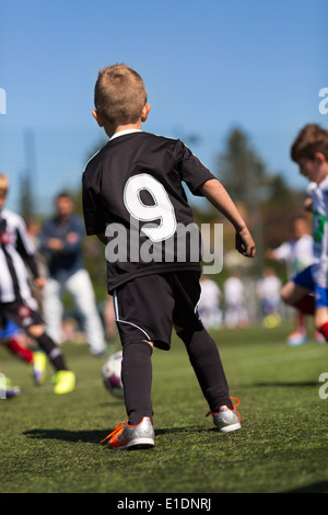 Kinder spielen Fußball im Freien an einem sonnigen Tag. Marken sind entfernt worden. Stockfoto