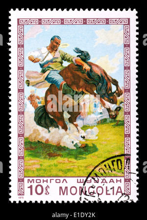 Briefmarke aus der Mongolei zeigt ein Bild eines Mannes, ein wildes Pferd zu zähmen. Stockfoto