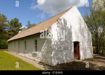 Traditionelles irisches Schulhaus, mit weiß getünchten Wänden und Strohdach in Ulster American Folk Park, Nordirland Stockfoto