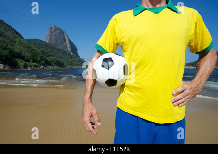 Brasilianischer Fußballspieler stehend mit Fußball im Praia Vermelha Red Beach vor Pao de Acucar Zuckerhut Rio Stockfoto