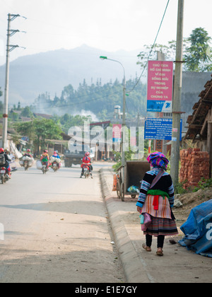 A Straßenszene in Bac Ha, Provinz Lao Cai, Vietnam.  Eine Blume Hmong-Frau geht im Vordergrund. Stockfoto