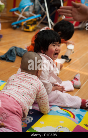 Kind weint beim Sitzen auf dem Boden oder an ein Waisenhaus in Peking Stockfoto