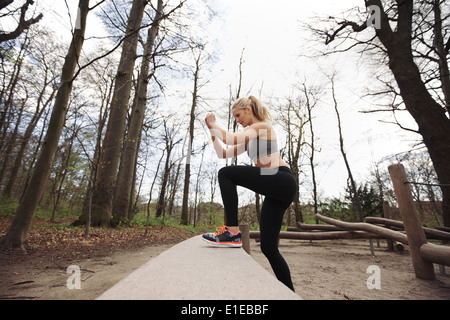 Fitness-Frau Intensivierung der Übung im Wald zu tun. Kaukasische weibliches Modell in der Natur trainieren. Stockfoto