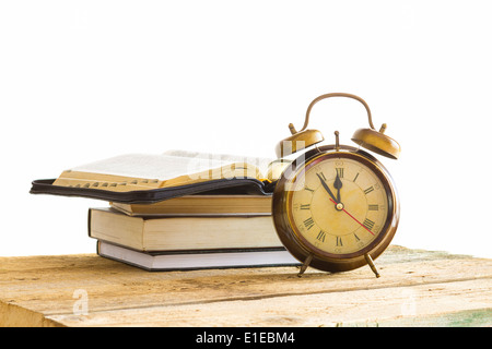 Offene Bibel mit Uhr auf Holz mit weißem Hintergrund Stockfoto