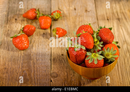 frische Erdbeeren in Holz Schüssel auf alten hölzernen Hintergrund Stockfoto