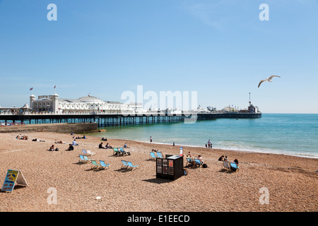 Menschen entspannen am Strand neben dem Pier von Brighton, East Sussex, UK Stockfoto