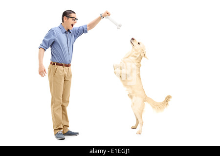 Junger Mann, einen Hund mit einem Knochen locken Stockfoto