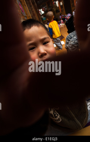 Kind für die Kamera mit den Händen in einem Waisenhaus in Peking Stockfoto