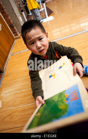 Kind hält ein Buch mit Illustrationen in einem Waisenhaus in Peking Stockfoto