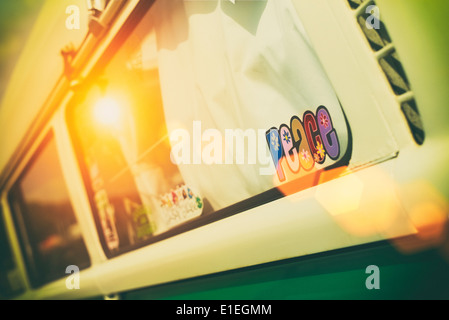 Frieden-Aufkleber im Fenster einen VW Campervan mit nostalgischen Filter hinzugefügt und düstere Sonne Streulicht. Stockfoto