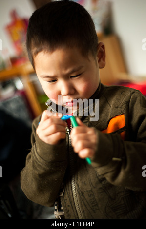 Kind in einem Waisenhaus in Peking hält eine Wachs Farbe während der Kunst-Klasse Stockfoto