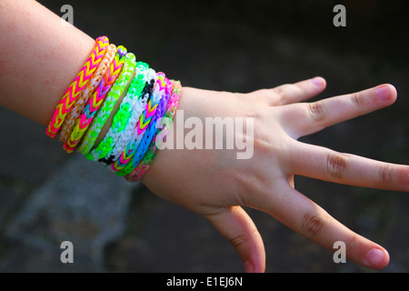 Junges Mädchen Angeberei Regenbogen Webstuhl Band Armbänder an ihrem Handgelenk Stockfoto