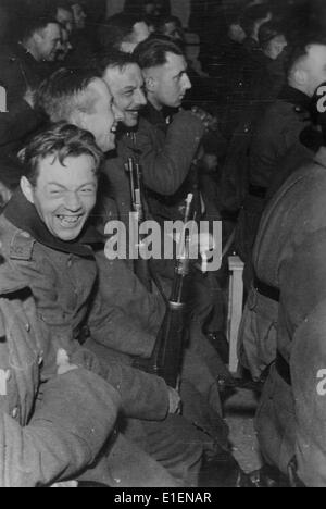 Deutsche Soldaten nehmen im Februar 1942 an einem Soldaten-Kabarett an der Ostfront Teil. Der ursprüngliche Text der Nazi-Propaganda auf der Rückseite des Bildes lautet: "Ein Blick in den Zuschauerbereich während einer Darbietung eines Soldaten-Kabaretts an der Ostfront. Die Soldaten amüsieren sich schwul, aber selbst hier im Theater geben sie ihre Gewehre nicht auf." Fotoarchiv für Zeitgeschichtee - KEIN KABELDIENST Stockfoto