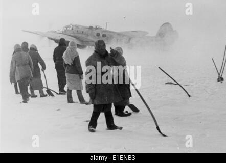 Das Bild aus einem Nazi-Nachrichtenbericht zeigt sowjetische Kriegsgefangene, die im Winter von deutschen Soldaten während Schneeräumarbeiten auf dem Flugplatz an der Ostfront am Don im Januar 1943 gefangen genommen wurden. Der Originaltext auf der Rückseite lautet: "Abflug trotz Schnee und Eis. Viele Gefängnisse mussten einspringen, um Schnee vom Flugfeld auf dem Don zu entfernen. Jetzt können Kampfflugzeuge für Angriffe auf die sowjetischen Positionen starten." Fotoarchiv für Zeitgeschichtee - KEIN KABELDIENST Stockfoto