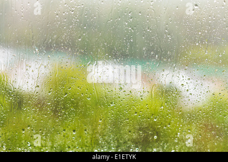 Regen Sie Regentropfen auf der Fensterscheibe in Sommertag vor Fenster- Stockfoto