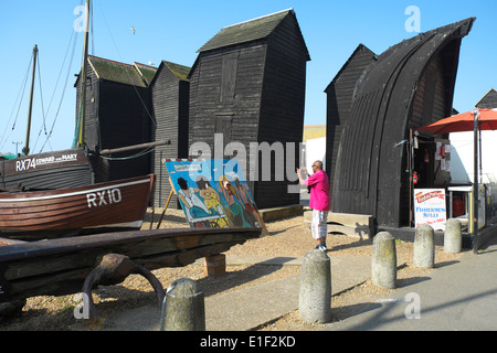 Besucher nehmen Momentaufnahme der Mädchen auf der Suche durch Cartoon Bild Bodyboard von den traditionellen schwarzen Net Hütten, Hastings Altstadt Stockfoto