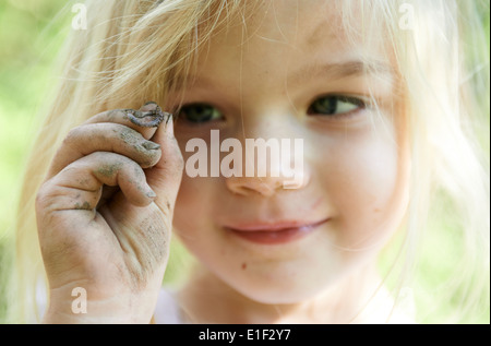 Kind blondes Girl Holding Wurm draußen im Garten, Porträt, Sommer Stockfoto