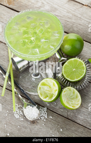 Klassischen Margarita cocktail mit salzigen Rand auf Holztisch mit Limetten und trinken Utensilien Stockfoto