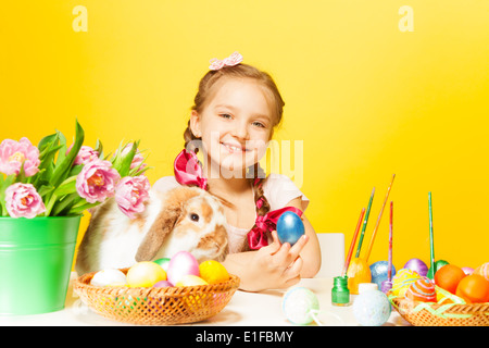 Lächelndes Mädchen mit östlichen Eiern und niedlichen Kaninchen Stockfoto