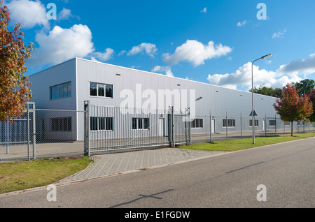 moderne Fassade eines Industriebaus, umgeben von einem Zaun mit Tor Stockfoto