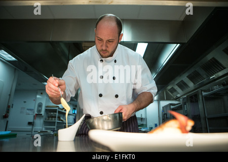 Koch in der Küche und bereitet eine Mahlzeit kochen Gießen sauce Stockfoto