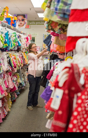Denver, Colorado - eine schwangere 26-jährige Frau Shops für Baby Kleidung bei einem Weiterverkauf Shop. Stockfoto