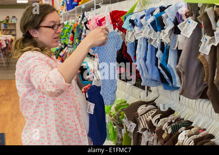 Denver, Colorado - eine schwangere 26-jährige Frau Shops für Baby Kleidung bei einem Weiterverkauf Shop. Stockfoto