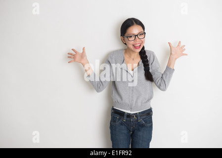 asiatische junge Studentin in Überraschung Aussehen mit einfarbigen Hintergrund Stockfoto