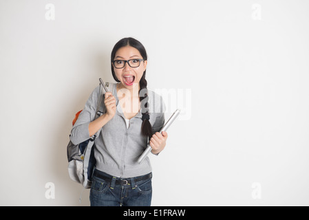 asiatische junge Studentin in Überraschung Aussehen mit einfarbigen Hintergrund Stockfoto