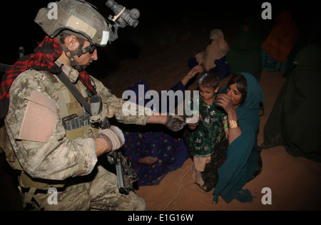 Afghan National Army Soldaten geben ein Kind Süßigkeiten während a einer nächtlichen Suche nach Aufständischen Taliban mit US-Armee Soldaten 8. August 2013 in Zharay district, Provinz Kandahar, Afghanistan. Stockfoto