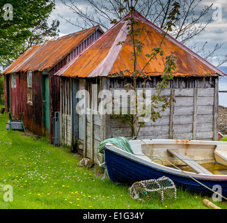 Hölzerne Hütten auf der Isle OF Skye mit Blechdach, ein Schiff legt an der Seite von ihnen warten auf Fisch zu gehen. Stockfoto