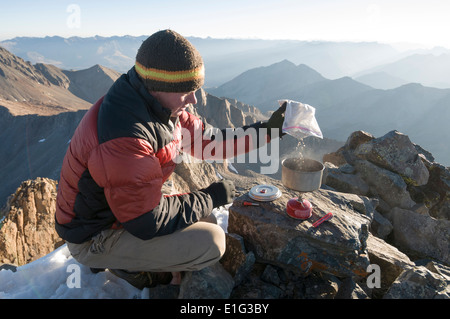 Ein Mann, kochendes Wasser auf Campstove auf dem Gipfel des Mount Wilson in der Nähe von Tellride, Colorado. Stockfoto