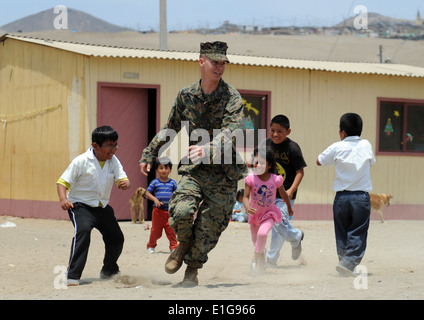 U.S. Marine Corps CPL Paul D. Fuit, mit der 2. Marine Logistics Group, läuft mit peruanischen Kindern bei Elias Aguirre Romero E Stockfoto