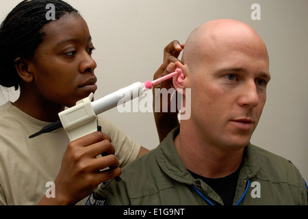 US Air Force Senior Airman Jessica Ervin, links, spritzt eine Silikonmasse ins Ohr Kanal von Kapitän Justin Puro am McEnti Stockfoto