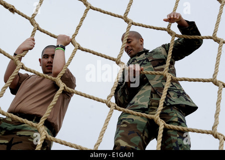 U.S. Navy Chief Special Warfare Betreiber David Goggins, Recht, klettert ein Cargo net Hindernis mit einer Make-A-Wish Foundation emp Stockfoto