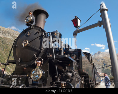 Der historische Dampfzug der Furka stoppt bei Gletsch, Schweiz, in den Alpen 1760m über dem Meeresspiegel, um neue Kohle und Wasser kostenlos. Stockfoto