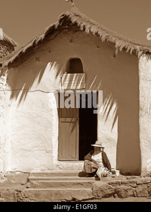 Eine Atacapeno Frau sitzt vor der Iglesia San Carlos im Dorf Machuca, Atacamawüste, Chile Stockfoto