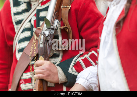 Ein Soldat gekleidet in traditionellen 17. Jahrhundert englische Armee Rotrock Uniform hält eine Steinschlossmuskete geschultert. Stockfoto