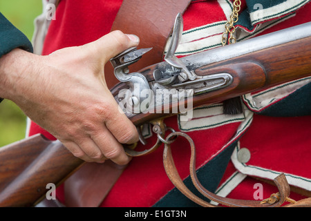 Ein Soldat gekleidet in traditionellen 17. Jahrhundert englische Armee Rotrock einheitliche laden eine Steinschlossmuskete. Stockfoto