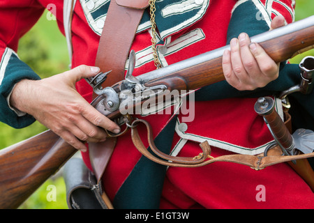 Ein Soldat gekleidet in traditionellen 17. Jahrhundert englische Armee Rotrock einheitliche laden eine Steinschlossmuskete. Stockfoto