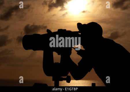 10.U.S. Marine Seemann Kyle Taylor, ein Spezialist Operationen beobachtet vorbeifahrende Schiffe durch die? Große Augen? während des Sonnenuntergangs an Bord t Stockfoto