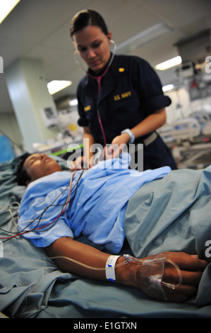 Lt. CMdR Sarah Blackowicz, Recht, prüft ein Patient auf der Intensivstation nach der Operation an Bord der Hospita Atmung Stockfoto